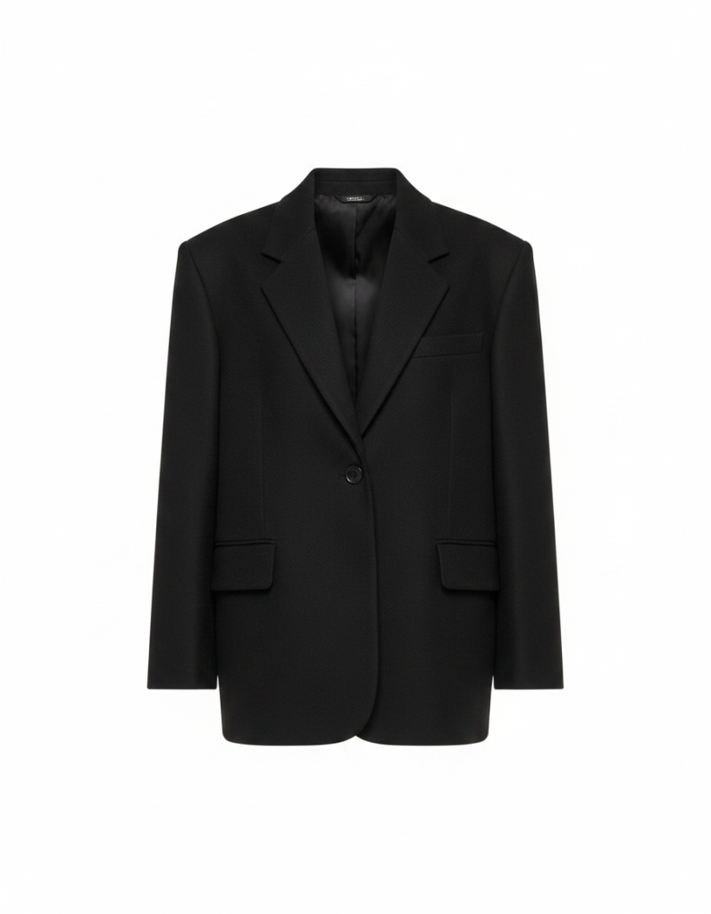 Blazer: Schwarz, oversized, tief sitzende Schulter — die Klammer über dem Bruch.